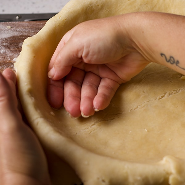 Pressing a rolled out sheet of pie dough into a pie plate.