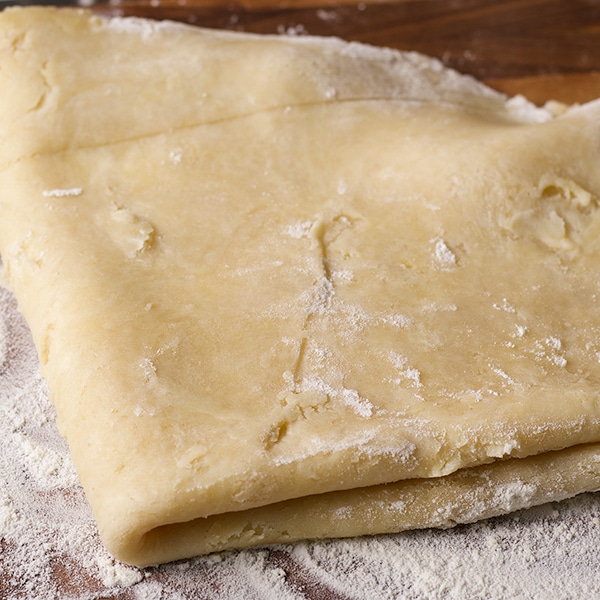 Folding rolled out pie crust pastry before placing it in a pie plate to bake.