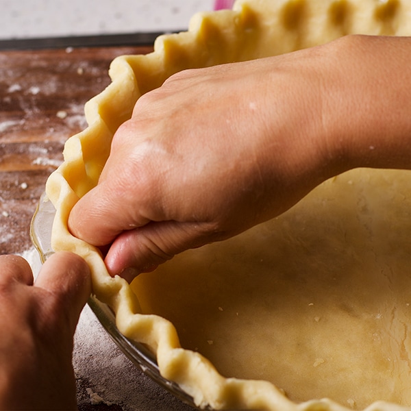 Crimping the edges of a pie crust before baking.