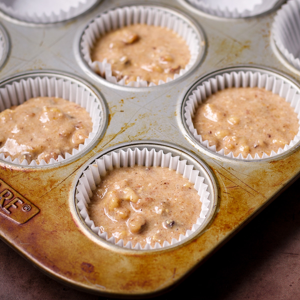 A muffin pan filled with gluten free banana nut muffin batter.