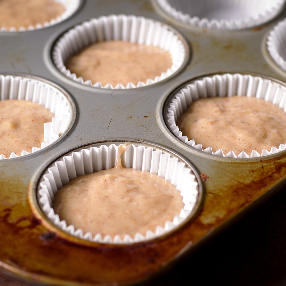 A muffin pan filled with raw muffin batter ready to bake.
