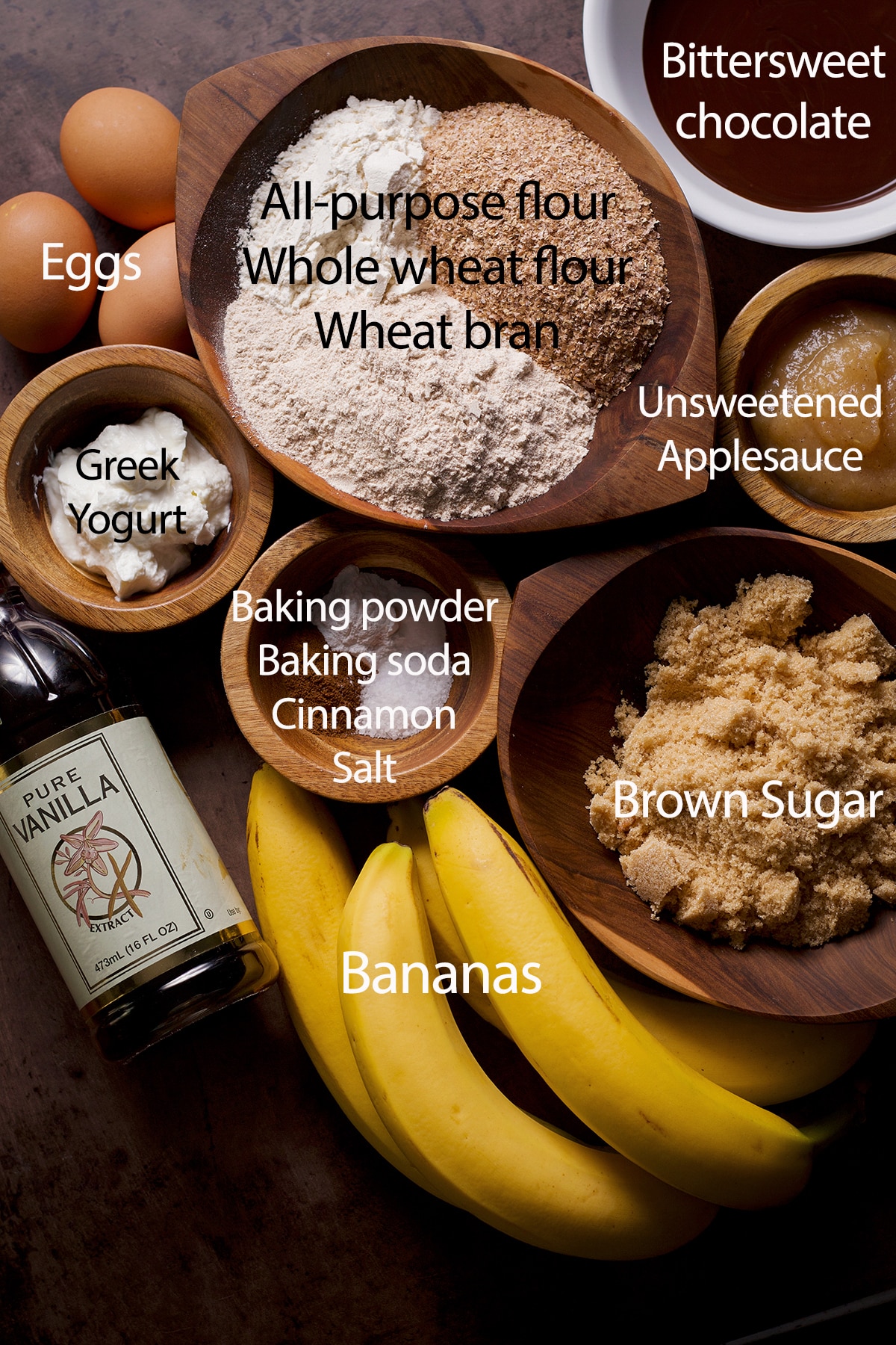 All of the ingredients you need to make these healthy chocolate banana breakfast muffins displayed on a wood table.