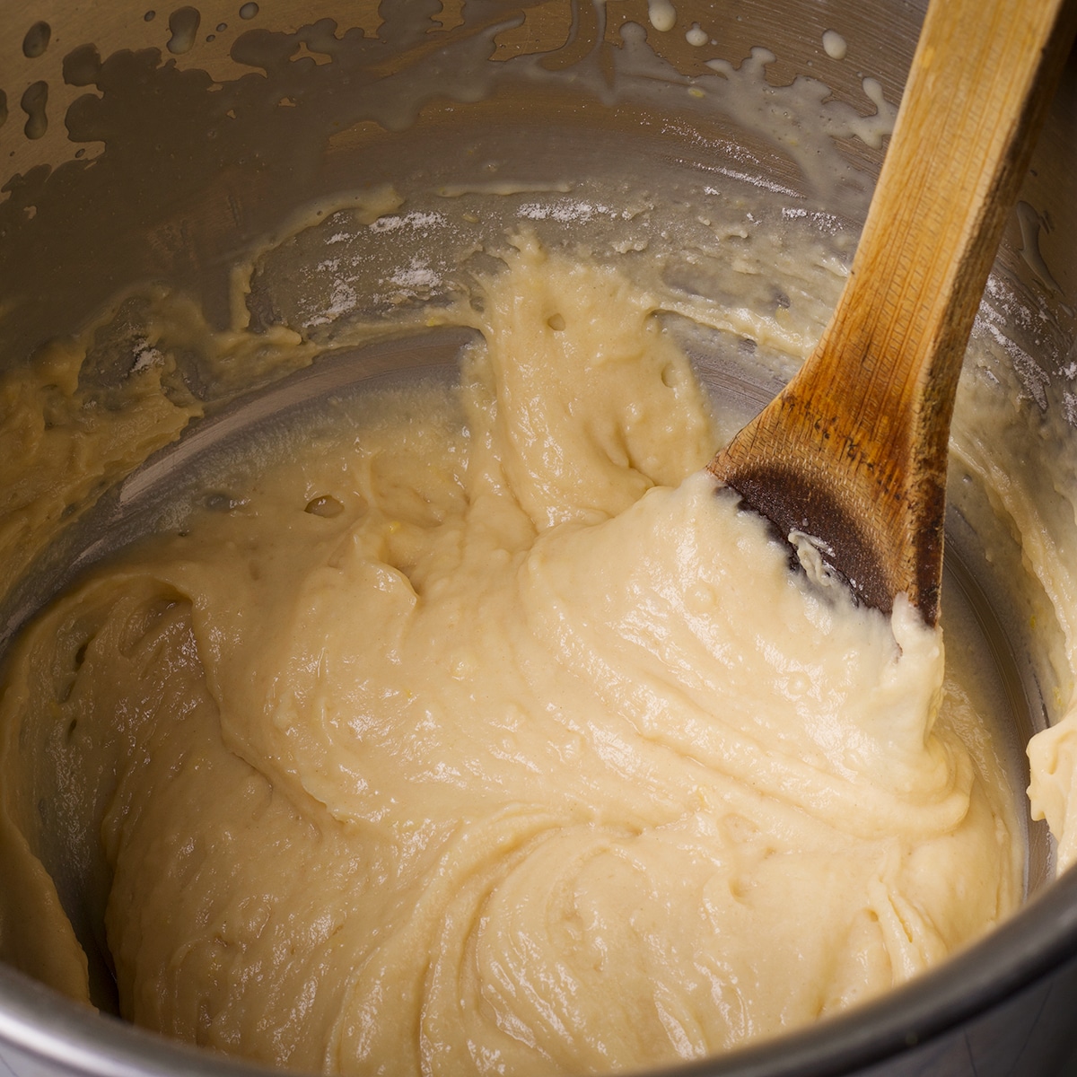 Using a wooden spoon to blend the dry ingredients into the wet ingredients to make the batter for raspberry bread.