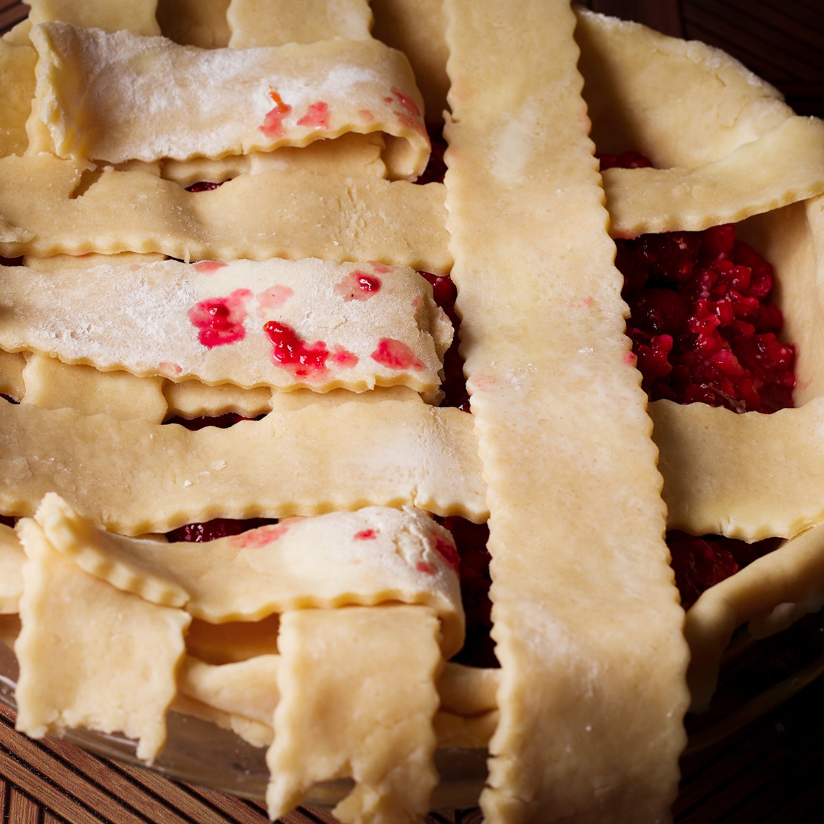 Weaving strips of pie dough over a pie to create a lattice pattern.