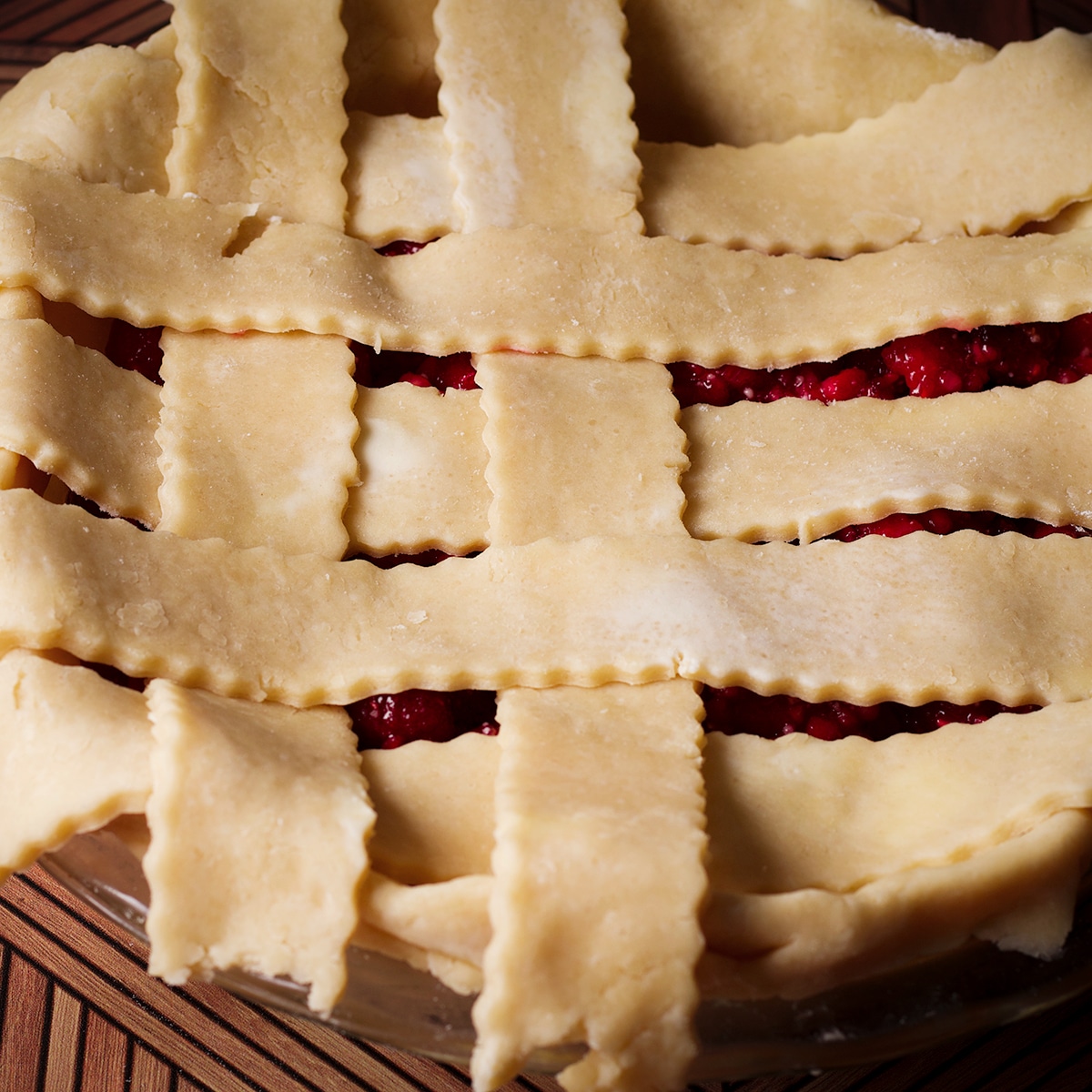 Weaving strips of pie dough over a pie to create a lattice pattern.