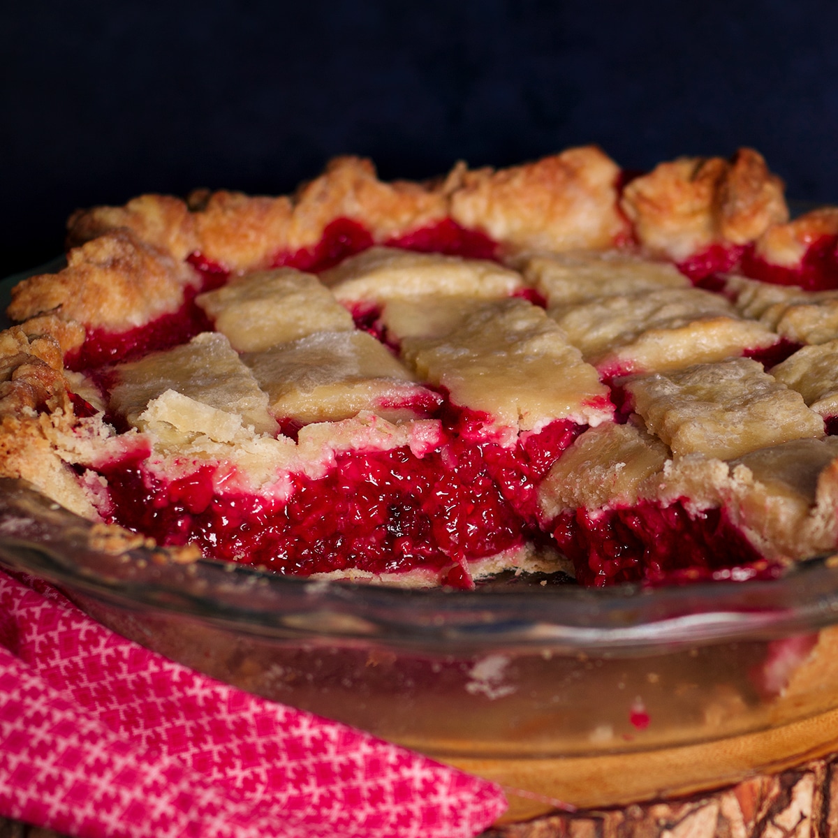 A raspberry pie with a couple of slices removed from it.