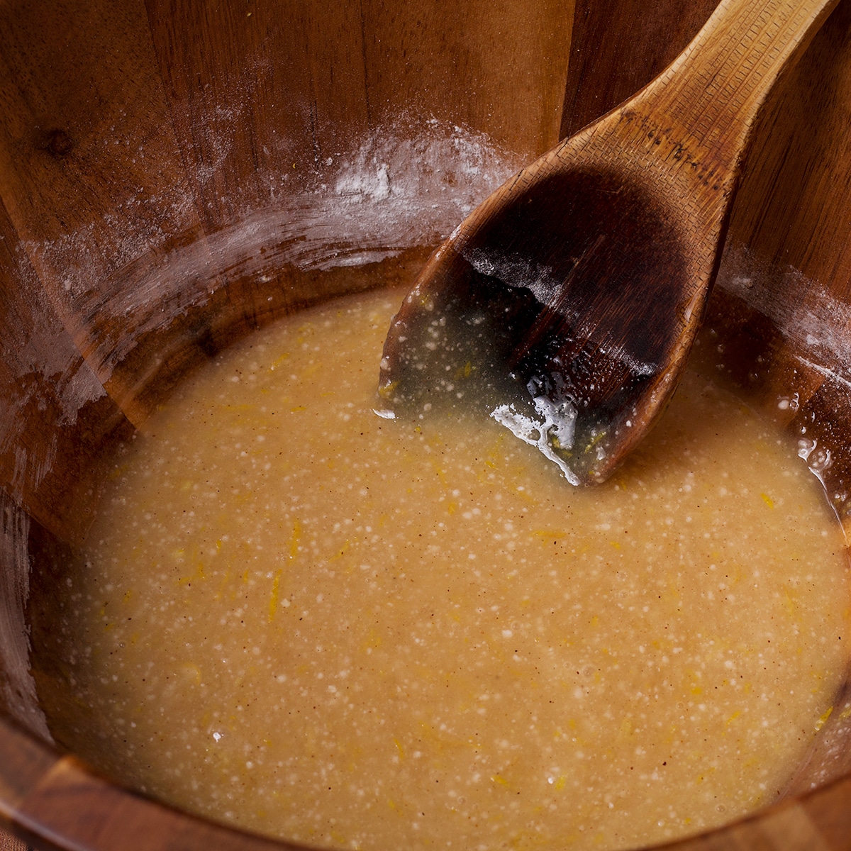 Using a wooden spoon to stir lemon juice, honey, and vanilla into the dry ingredients for raspberry pie filling. 