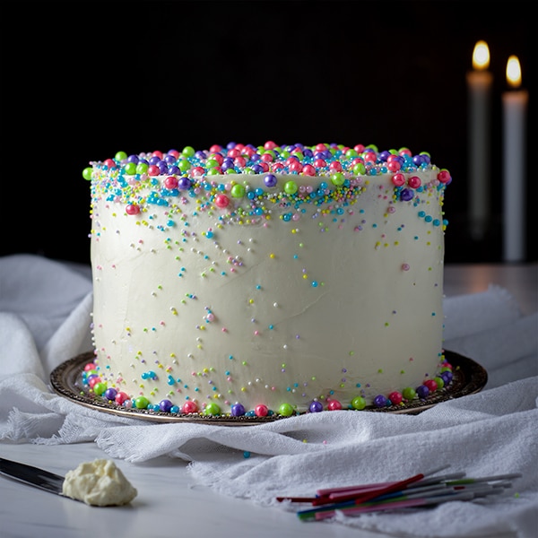 An iced vanilla layer cake decorated with sprinkles.
