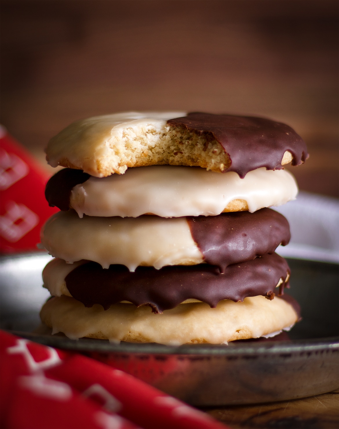 A stack of New York Black and White Cookies, the top cookie has a bite taken out of it.