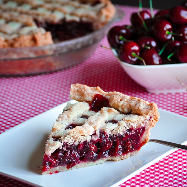 A slice of triple cherry pie on a plate, ready to eat.