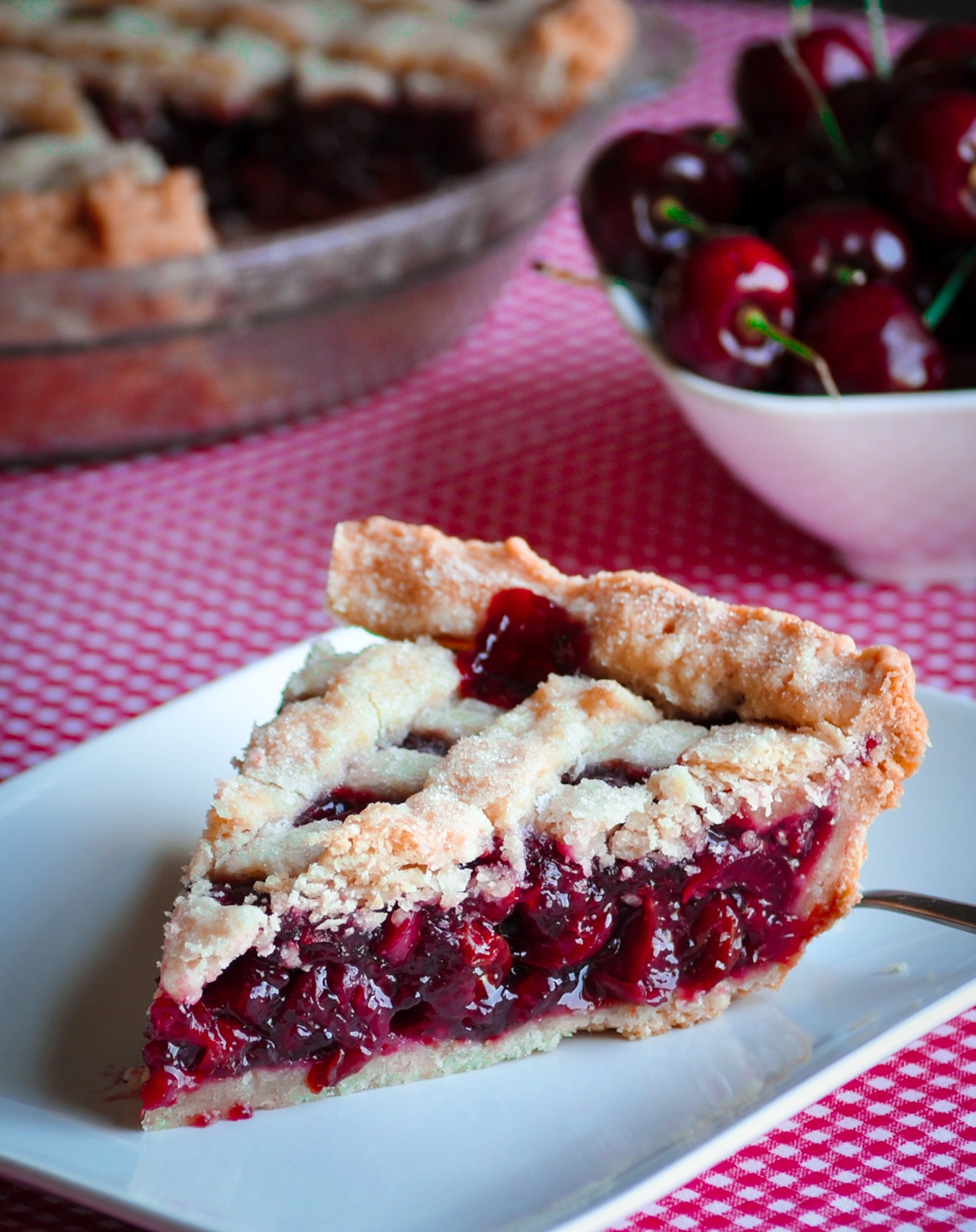 A slice of triple cherry pie on a plate, ready to eat.