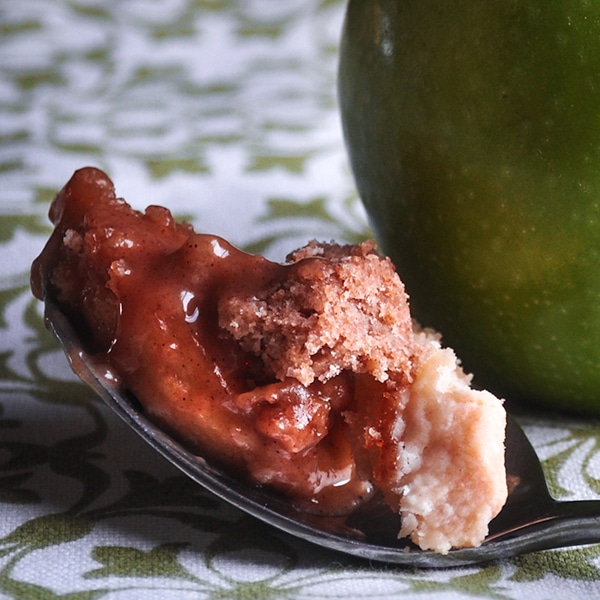 A bite of A bowl of Apple Slab Pie with caramel sauce and crumb topping.