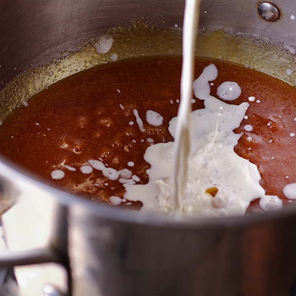 Pouring cream into caramel to make salted caramel sauce.