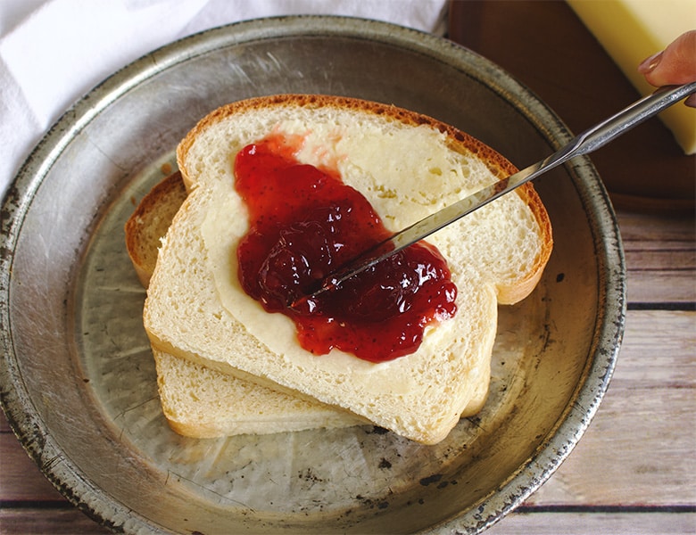 Spreading jam onto a slice of homemade bread