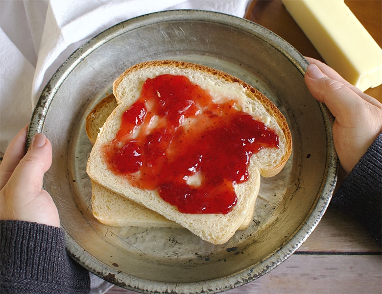Two slices of everyday homemade sandwich bread with butter and jam.