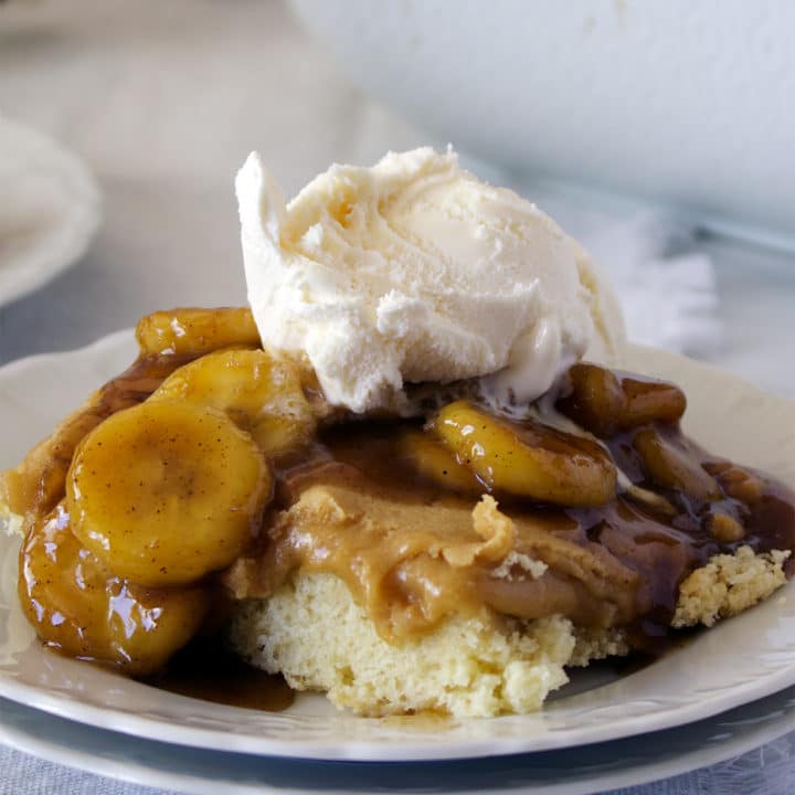 A plate of Bananas Foster Butter Cake with vanilla ice cream. {St. Louis Gooey Butter Cake with Bananas Foster Sauce}