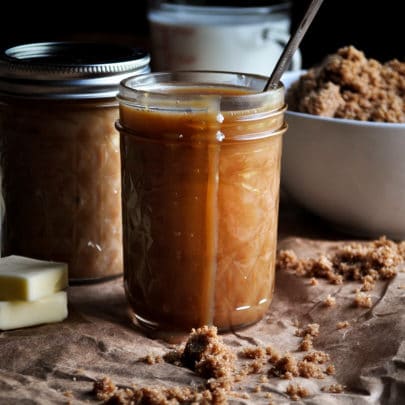 A jar of butterscotch sauce with some sauce dripping over the side.