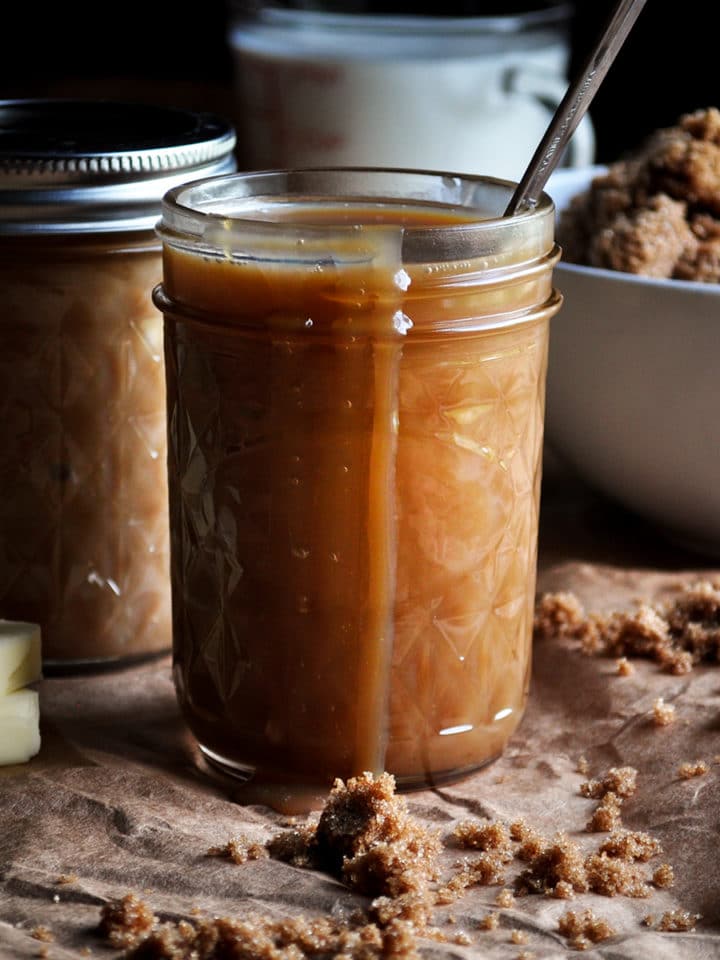 A jar of butterscotch sauce with some sauce dripping over the side.