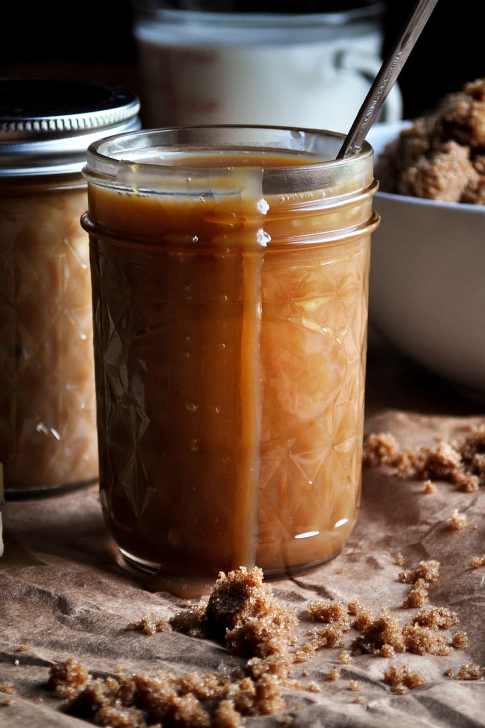 A jar of butterscotch sauce with some sauce dripping over the side. 