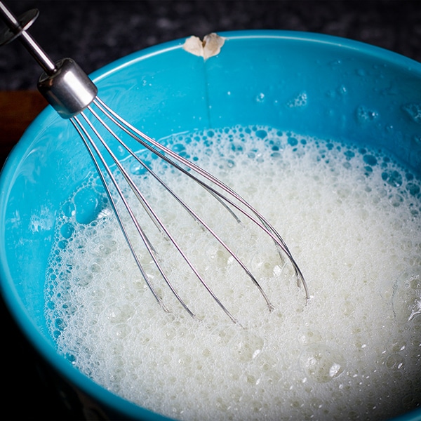Beating egg whites with an electric mixer until frothy.