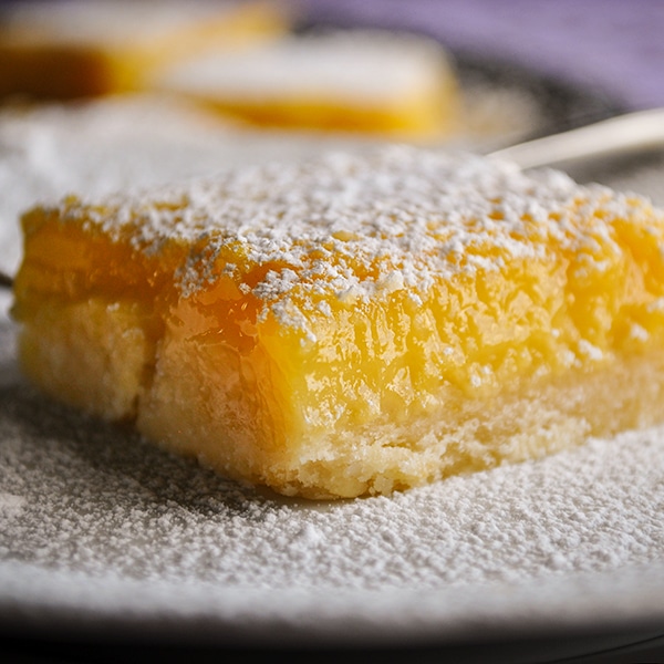 Lemon bars on a serving platter, sprinkled with powdered sugar.