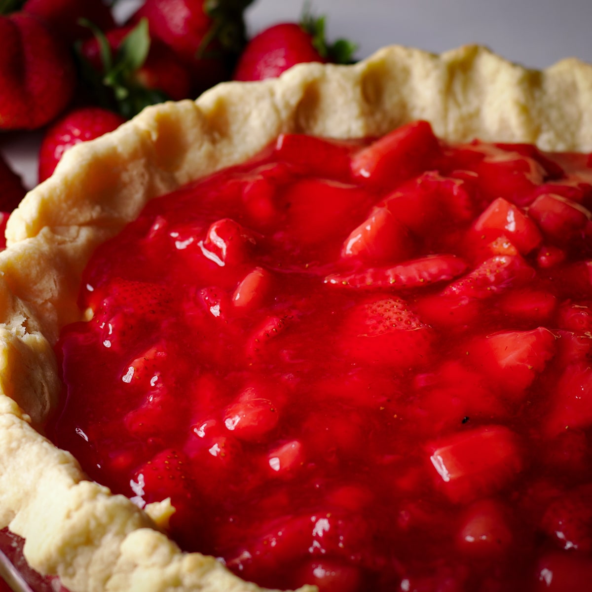 A partially baked pie crust that's been filled with pastry cream and strawberry pie filling.