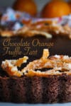 A chocolate orange truffle tart on a serving tray, decorated with candied orange peel.