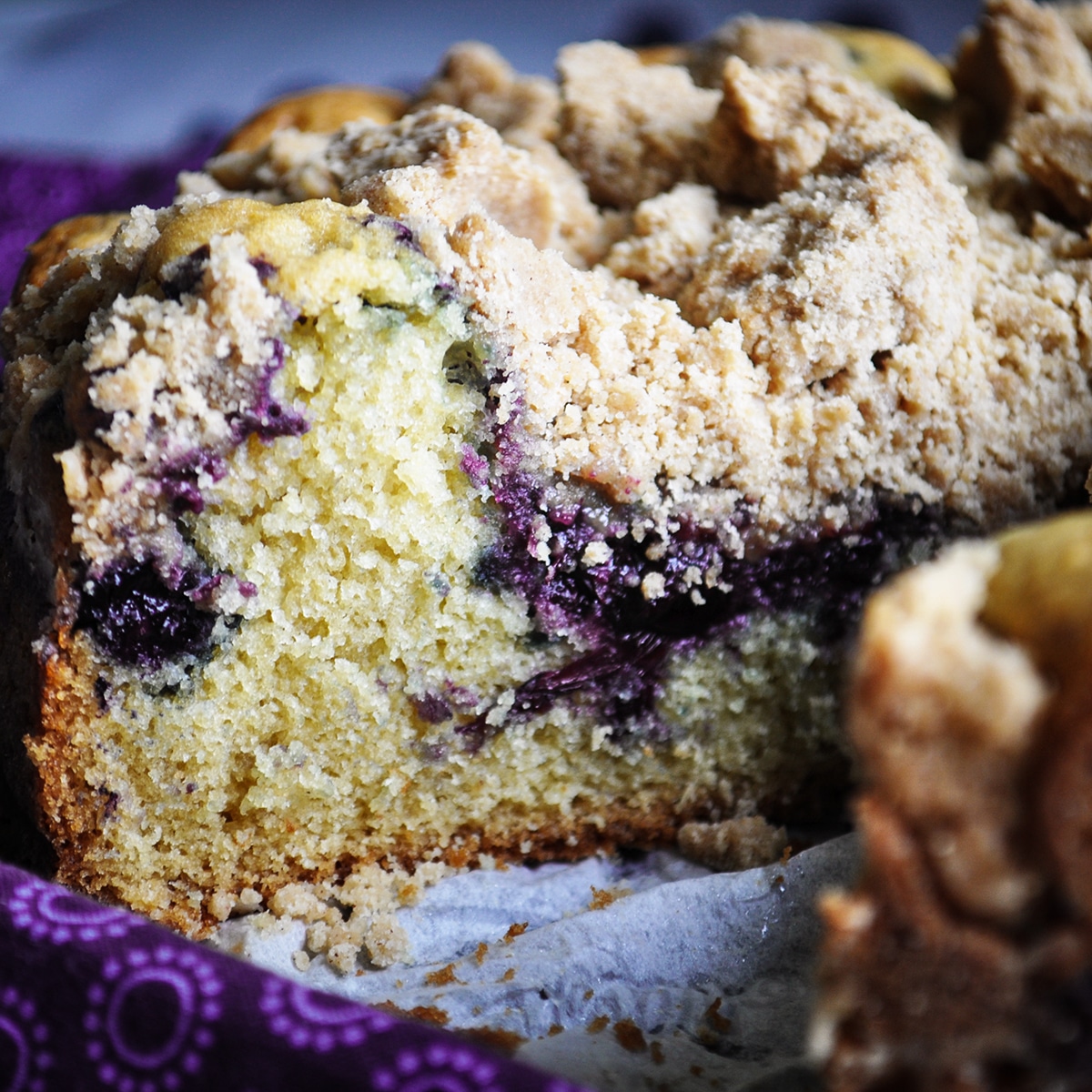 A blueberry coffee cake with one slice cut from it.