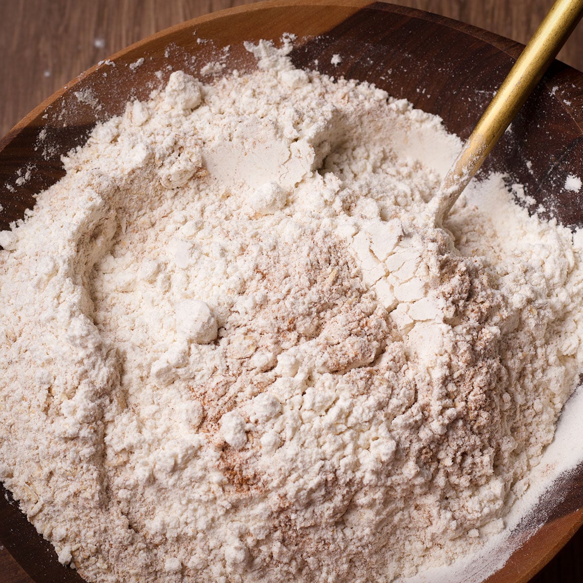 Using a spoon to stir whole wheat flour, all-purpose flour, baking soda, and salt together in a bowl.