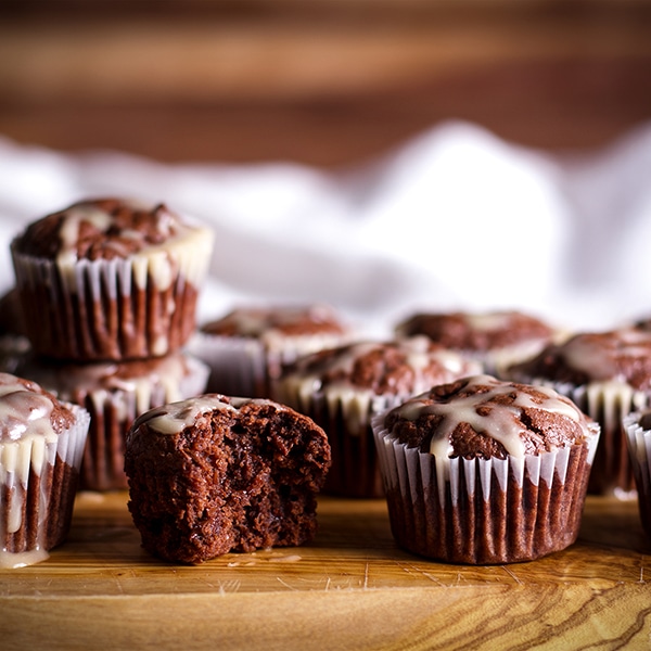 A tray of mini chocolate muffins with vanilla glaze.