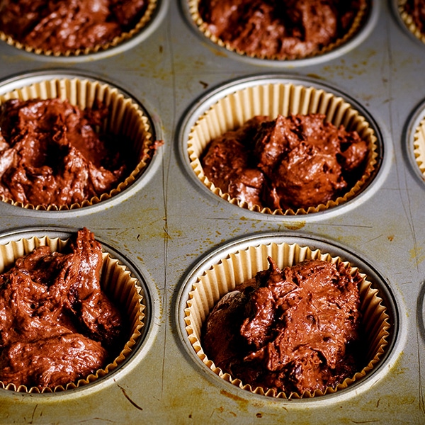 Filling a muffin tin with batter to make Double Chocolate Muffins.