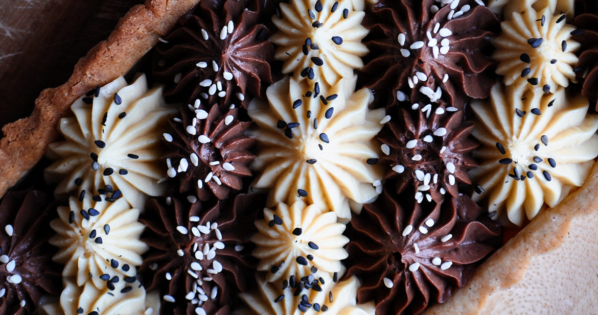A black and white chocolate tahini tart with alternating stripes of white and dark chocolate filling.