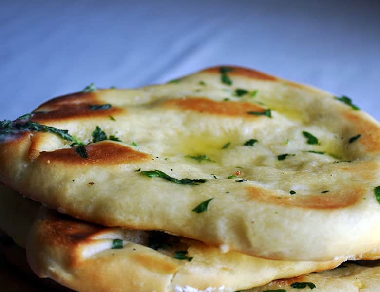 Homemade garlic naan brushed with butter and parsley.