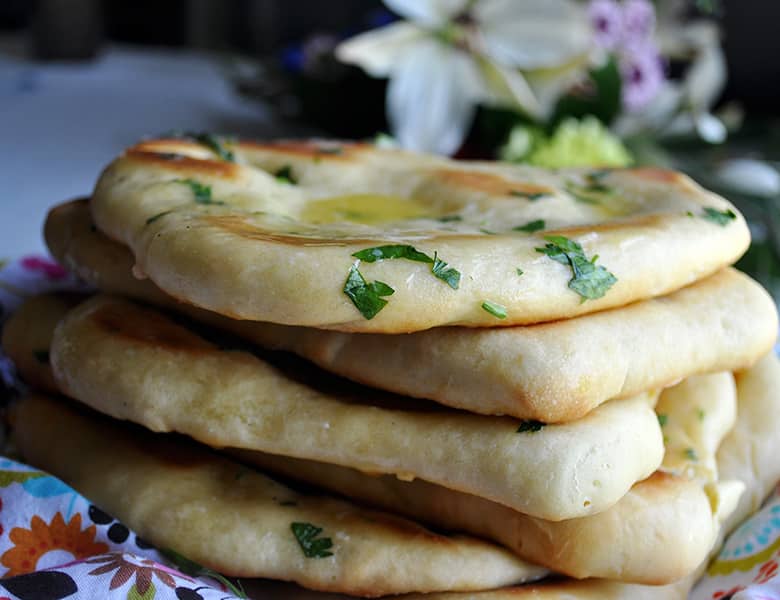 A stack of homemade garlic naan breads.