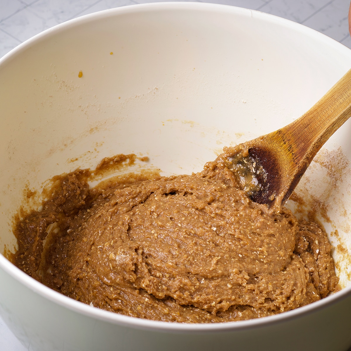 Using a wooden spoon to mix the wet and dry ingredients for muffin batter.