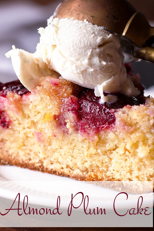 A slice of almond plum cake topped with a scoop of vanilla ice cream,.