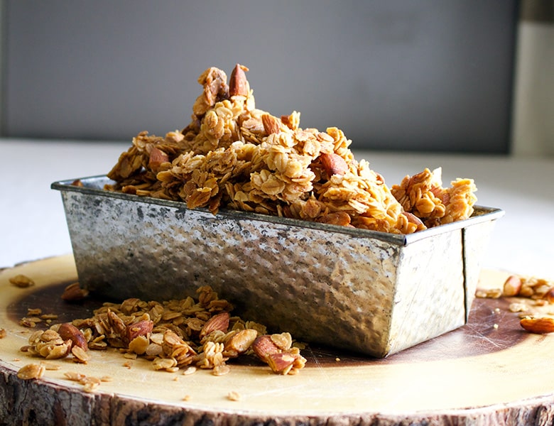 A tin loaf pan filled to overflowing with homemade maple almond granola.