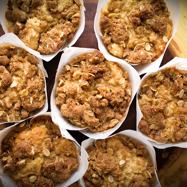 A wood tray piled with freshly baked apple cinnamon muffins with streusel.