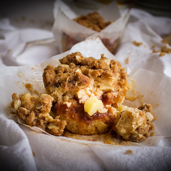 An apple cinnamon muffin with apple butter and streusel broken apart so you can see the inside.