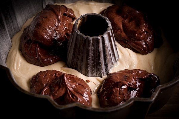 Filling a bundt pan with cake batter to make marble cake.