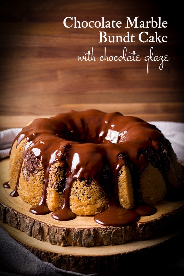 A marble cake covered in chocolate glaze on a wood tray.