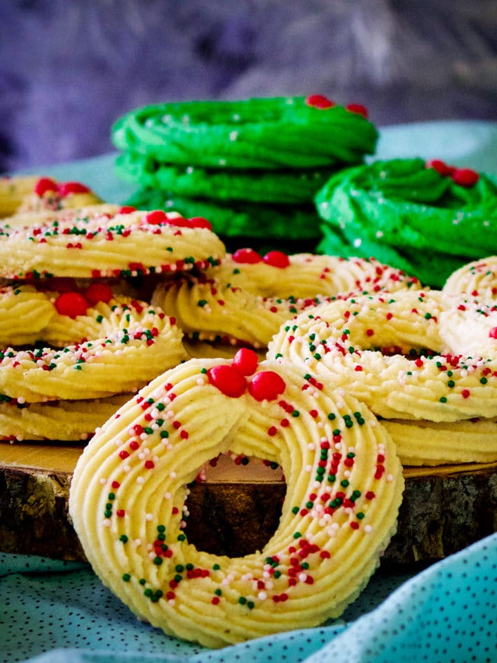 A tray stacked with Spritz cookies shaped like Christmas wreaths.
