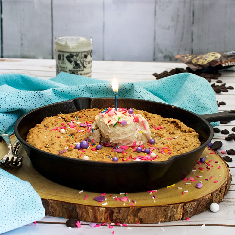 A large skillet cookie with chocolate chips and oatmeal, with a scoop of vanilla ice cream in the center and sprinkles.