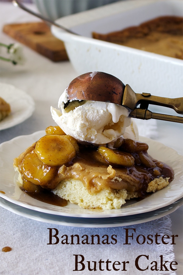 Someone using an old fashioned ice cream scoop to top a piece of bananas foster cake with a scoop of ice cream.
