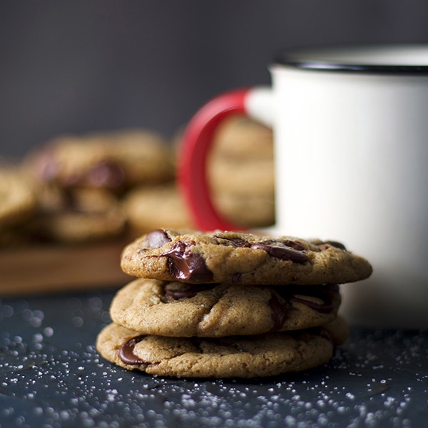 A stack of soft chocolate chip cookies and a mug of milk.