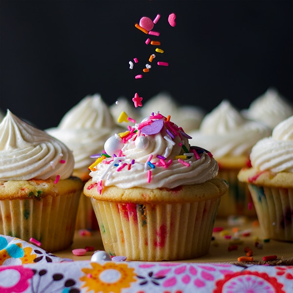 Adding sprinkles to the top of Funfetti Cupcakes with Classic American Buttercream