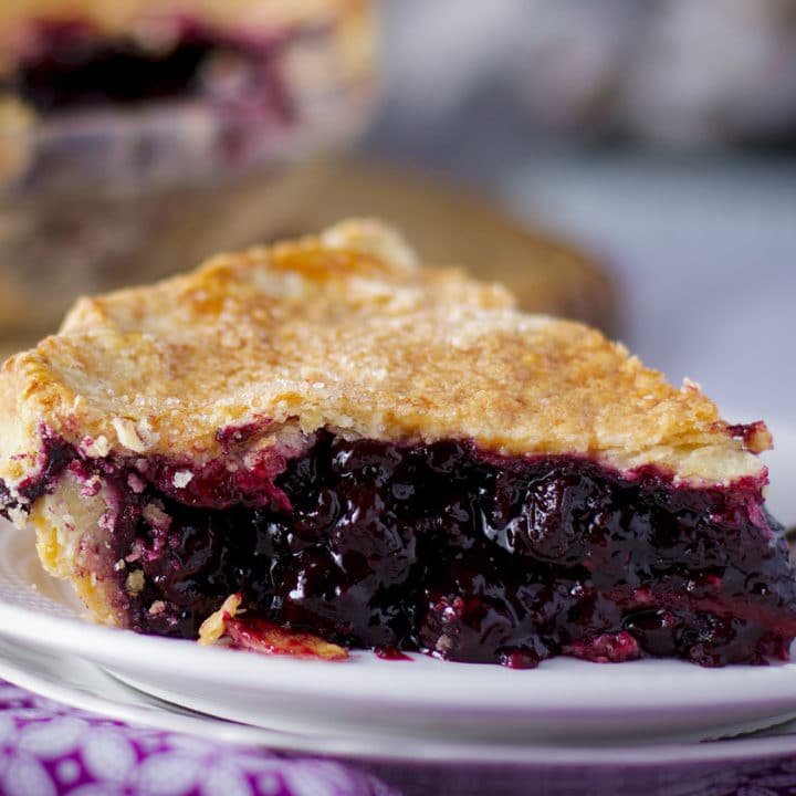A freshly baked slice of homemade blueberry pie on a plate, ready to eat.