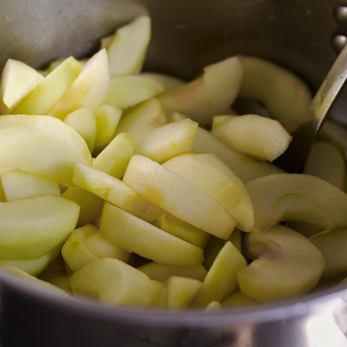 A saucepan filled with sliced green apples.