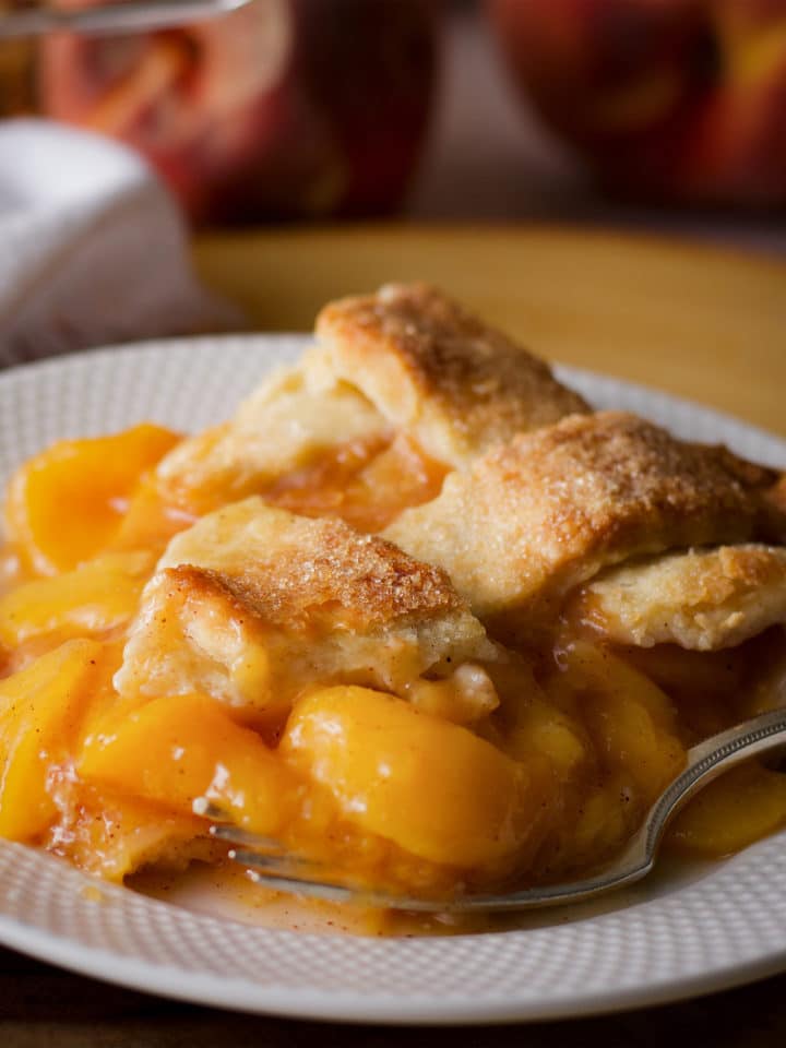 A slice of peach pie with a lattice crust on a plate.