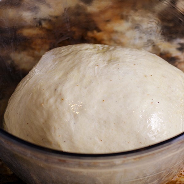 Bread dough that's rising in a glass bowl.